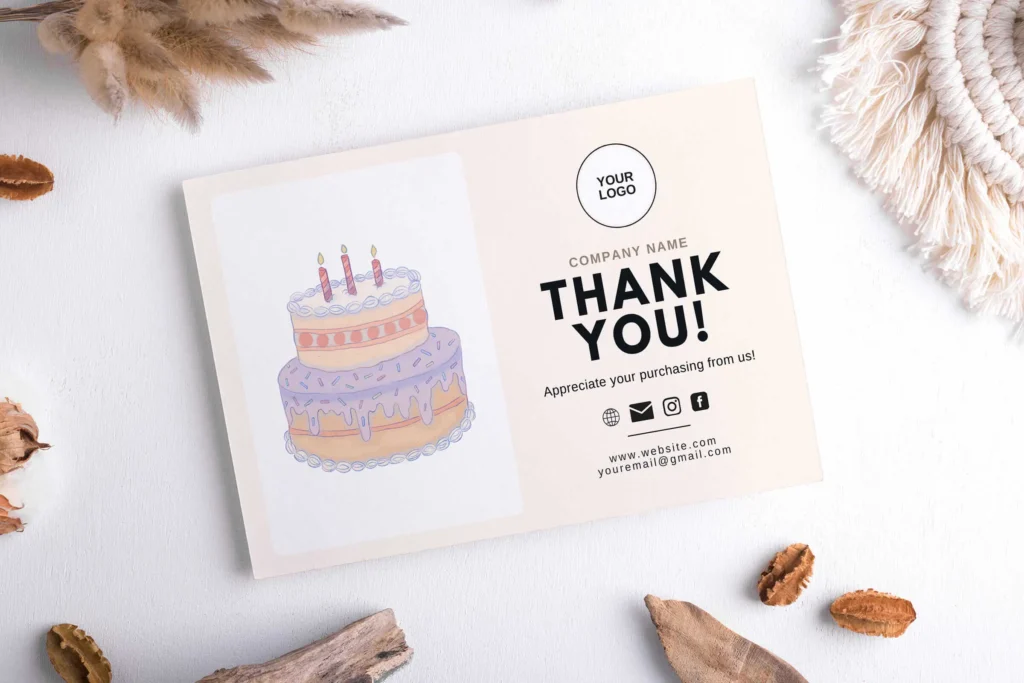 Thank you card with purple cake illustration placed on white wooden surface with dried flowers and minimal decor.
